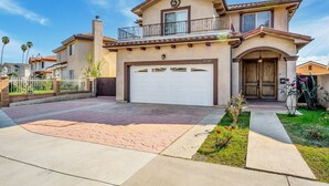 A two-story house with a garage, a balcony, and a well-maintained front yard.