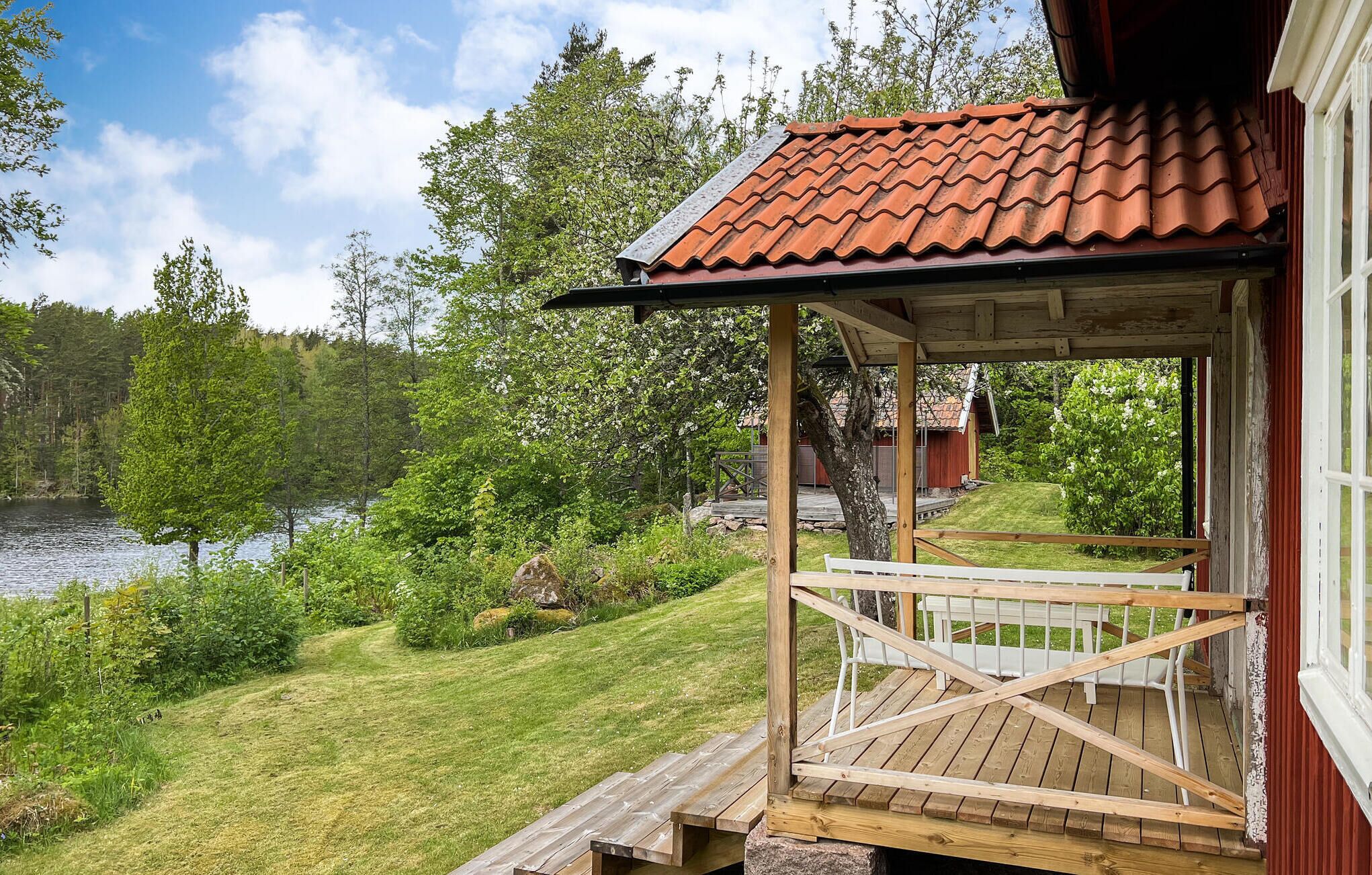A wooden deck with a railing, overlooking a lake and forested area.