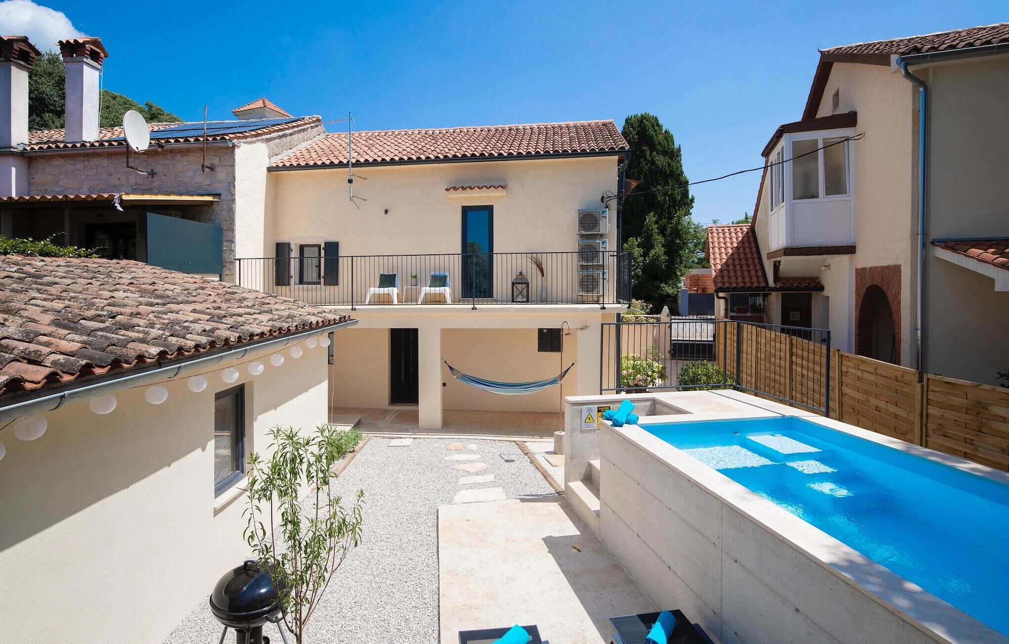 A residential property with a swimming pool, a hammock, and a small garden area.