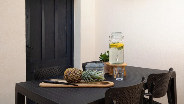 A table with a pineapple, a knife, a glass jar with a drink, and a small plant.