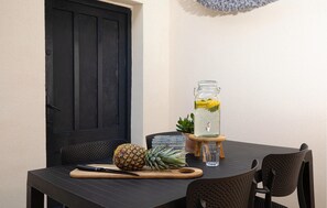 A table with a pineapple, a knife, a glass jar with a drink, and a small plant.