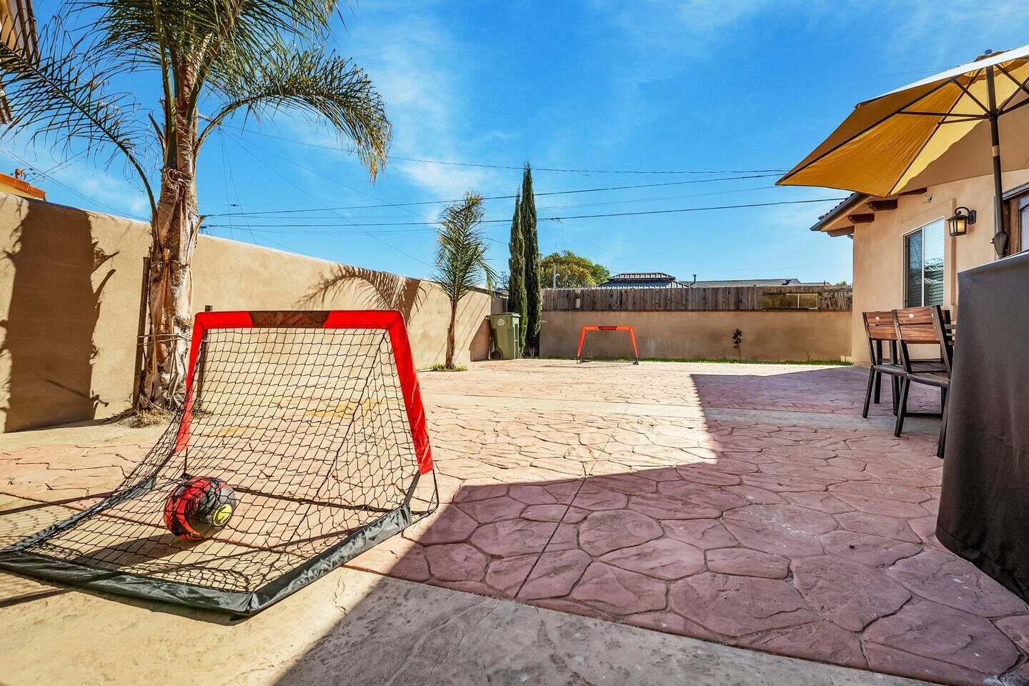 A patio with a soccer goal, outdoor furniture, and a palm tree.
