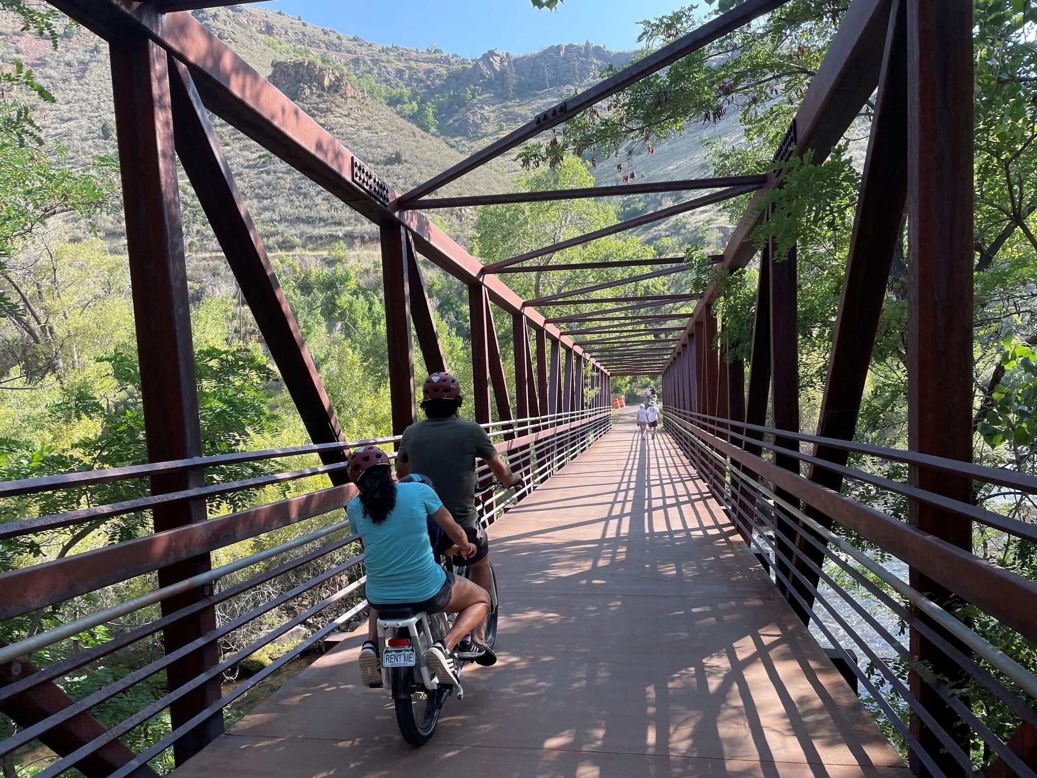 Un puente de metal con barandilla metálica y un camino pavimentado.