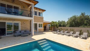 Une maison à deux étages dotée d’une piscine, d’un espace extérieur aménagé et d’un patio couvert.