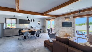Een moderne keuken met een eethoek, een stenen muur en uitzicht op de omgeving.