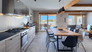 Een moderne keuken met een groot eiland, roestvrijstalen apparatuur en uitzicht naar buiten.