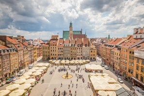 A spacious public square with numerous outdoor seating areas and a central fountain. - Lwowska Apartment (Warsaw)