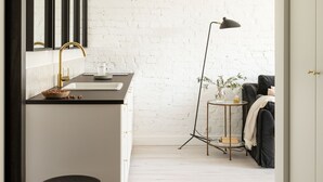 A modern bathroom with a white brick wall, a black and gold sink, and a stool. - Lwowska Apartment (Warsaw)