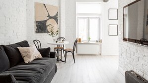 A modern living room with a black sofa, a white brick wall, and a large window. - Lwowska Apartment (Warsaw)