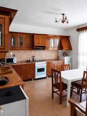 Une cuisine avec des meubles de rangement en bois, une cuisinière, un four à micro-ondes et un coin repas comprenant des chaises et une table.