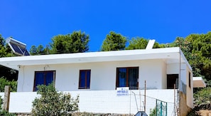 Un bâtiment blanc avec trois fenêtres, un panneau solaire et un panneau indicateur.