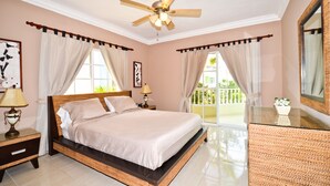 Ein Schlafzimmer mit Bett, Nachttischen, Deckenventilator und Balkonblick.
