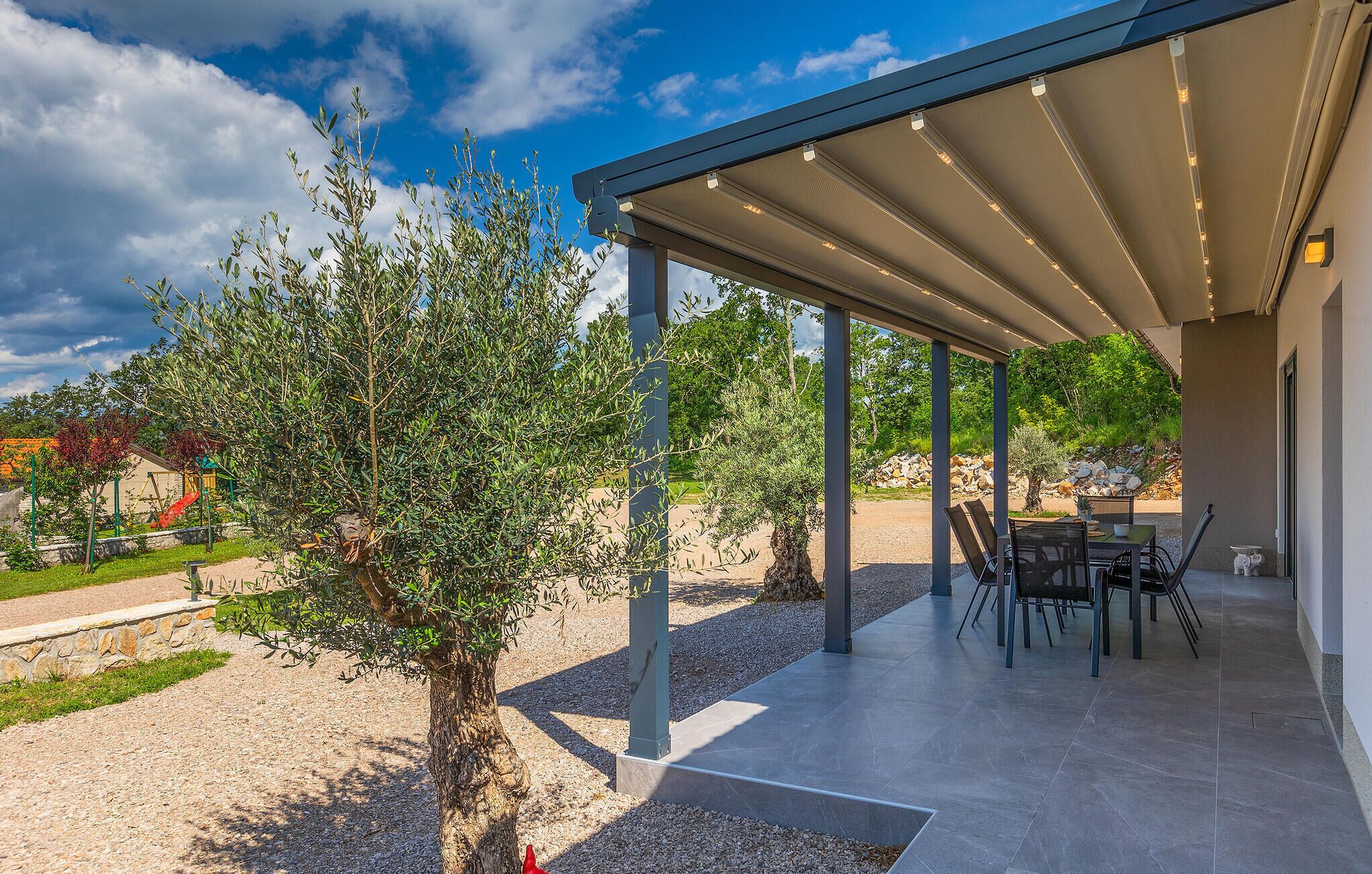 An outdoor patio area with a covered seating area, a table, and chairs.