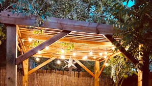 Une pergola en bois, décorée de guirlandes lumineuses et d’une étoile, entourée d’une clôture en bambou.