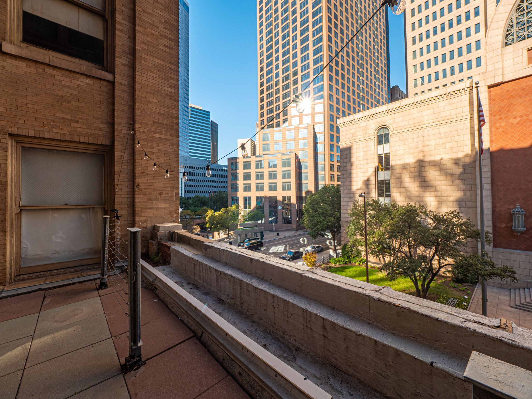 A view of a cityscape with tall buildings, a clear sky, and a sidewalk with steps leading to a building entrance.