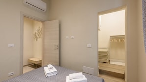 A hotel room with a bed, a desk, a chair, a wardrobe, and a bathroom visible through an open door. - Tripoli apartment in Florence by Mmega (Firenze)