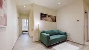 A hallway with a green sofa, a white rug, and a floor lamp. - Tripoli apartment in Florence by Mmega (Firenze)