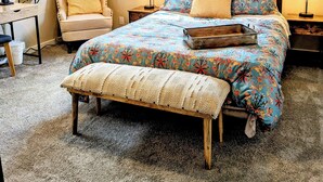 Un dormitorio con cama, una silla, un escritorio, un ventilador de techo y una ventana.