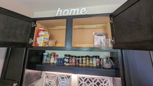 Una despensa de cocina con armarios abiertos, que contiene diversos alimentos y especias.