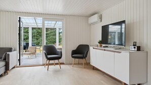 A modern kitchen with a large TV, a dining area with a table and chairs, and a sliding glass door leading to a patio.