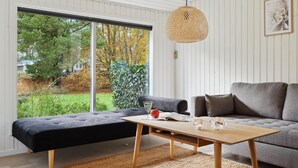 A modern living room with a grey sofa, a black ottoman, and a wooden coffee table.