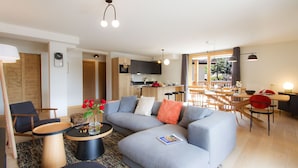 Una sala de estar moderna con un sofá gris, una mesa de centro y un comedor con mobiliario de madera.