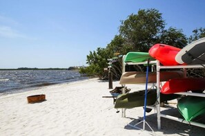 A beach with kayaks and a boat on a sandy shore.
