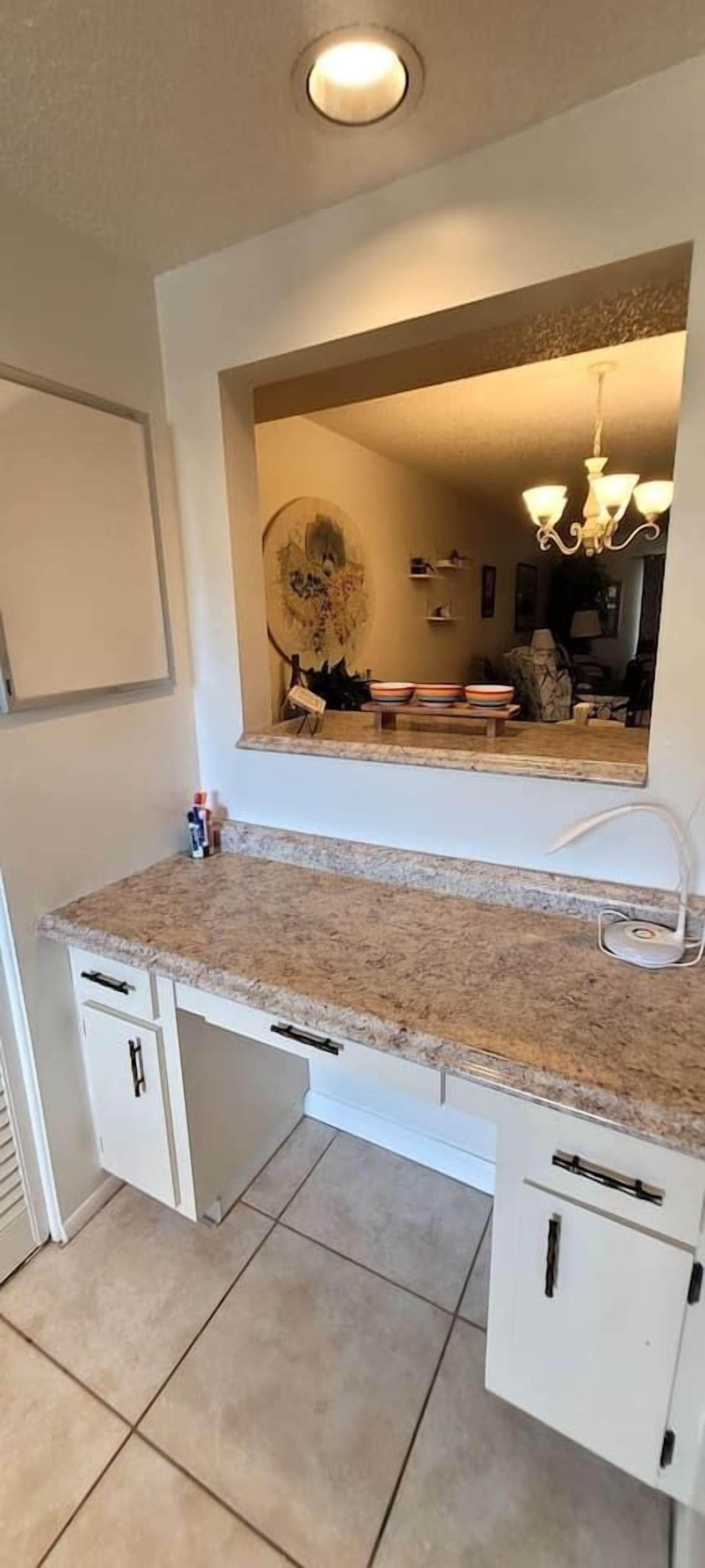 A kitchen with a granite countertop, white cabinetry, and a built-in oven.