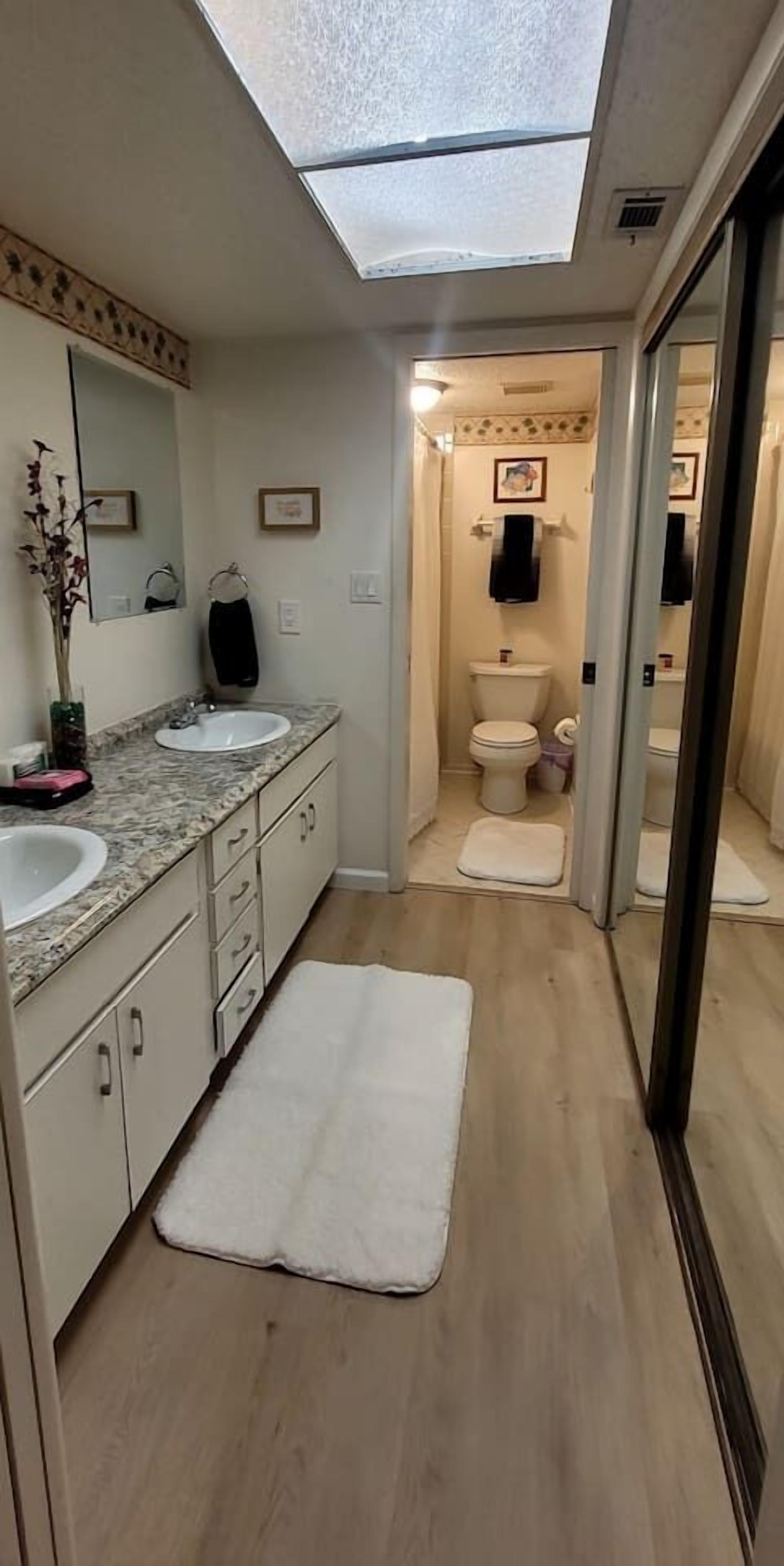 Ein modernes Badezimmer mit Dachfenster, zwei Waschbecken, einer Toilette und einer Duschkabine.