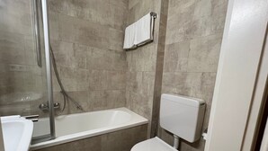 Et badeværelse med badekar, toilet og brusebad.