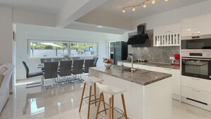 Una cucina moderna con un'isola centrale, sgabelli da bar e un'area pranzo con vista.