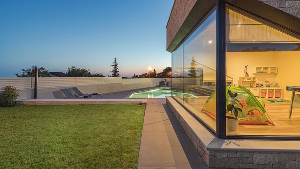 A modern house with a glass-enclosed patio, a swimming pool, and a view of the ocean. - Beautiful home in Porec (Porec)