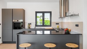 A modern kitchen with a central island, built-in oven, and stainless steel appliances. - Beautiful home in Porec (Porec)