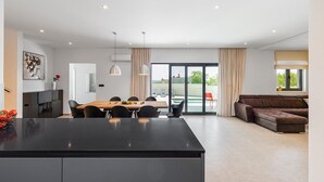 A modern kitchen with a central island, dining area with chairs, and a living room with a sofa. - Beautiful home in Porec (Porec)