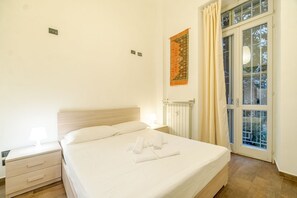 Ein Schlafzimmer mit einem Bett, einem Nachttisch und einem Fenster mit Vorhängen.