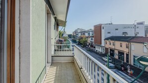 Un balcón con vistas a una calle de la ciudad, edificios y un cielo despejado.