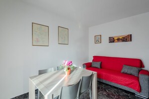 Et moderne værelse med et spisebord, stole, en rød sofa og to billeder i rammer på væggen.