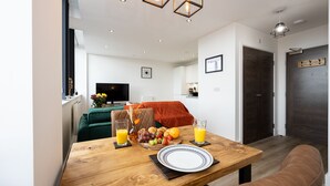 A dining area with a wooden table set for breakfast, including croissants, fruit, and orange juice. - Chic Industrial Luxury Stay (Stretford)