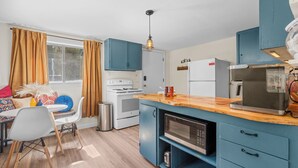 Una cocina compacta con armarios azules, una encimera de madera, una estufa y un microondas.