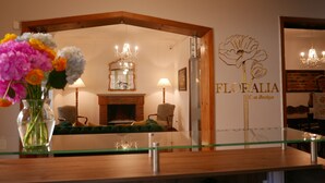 Ein Empfangsbereich mit einem Holzbüro, einem Spiegel, einer Chandelieber und einem floralen Logo an der Wand.