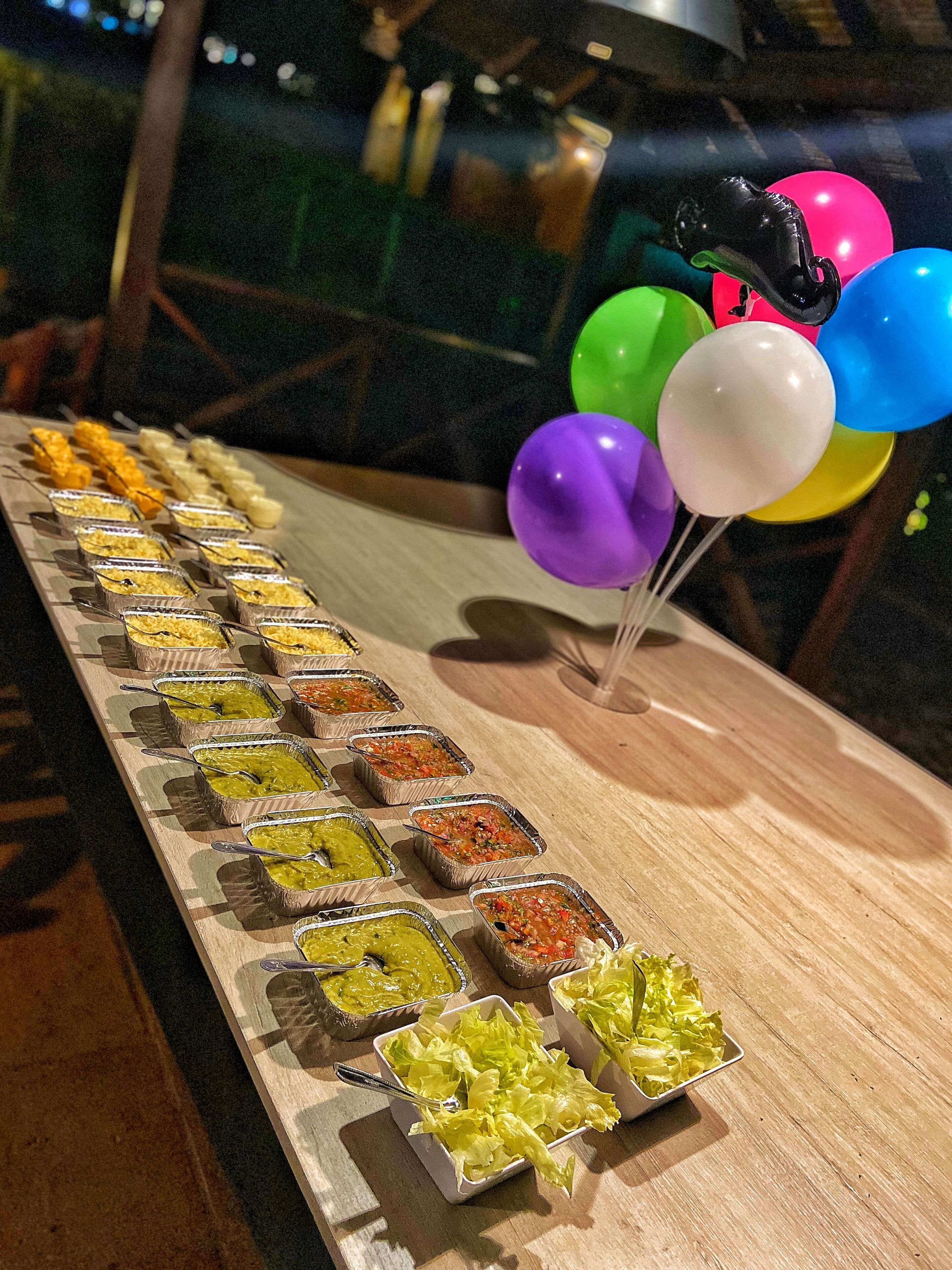 A buffet table with various food items and balloons.