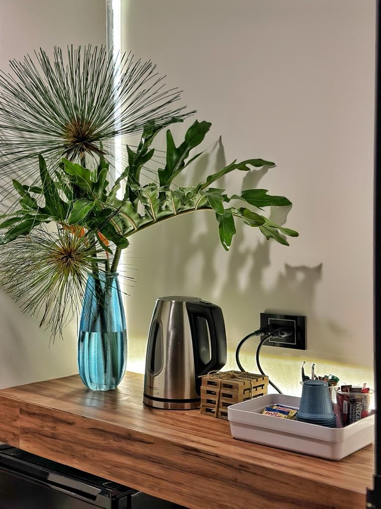 A kitchen counter with a coffee maker, a vase with a plant, and a tray with kitchen items.