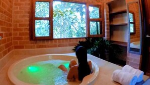 A room with a brick wall, a large window, a bathtub, and a towel on the floor. - Avalon Hotel Campestre en Jardin (Jardin)