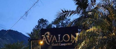 A gated entrance to a hotel named 'Avalon Hotel Campground' with a stone pathway leading to the gate.