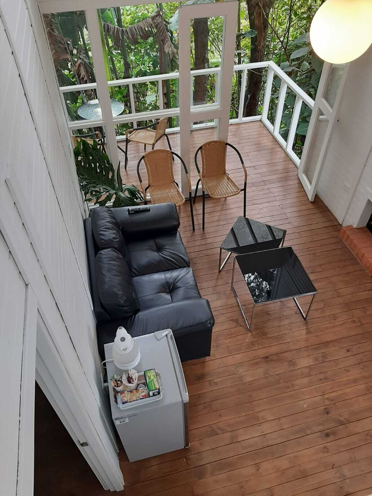 Un espace extérieur aménagé, abrité et doté d’un canapé, de deux fauteuils, d’une petite table et d’un réfrigérateur.