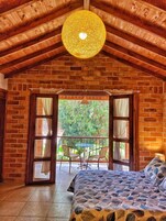 Una habitación acogedora con una cama, una mesa con sillas y vistas al verde exterior.