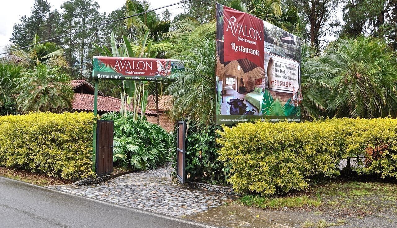 A hotel entrance with a sign for 'Avalon Hotel & Restaurant' and a large promotional banner.