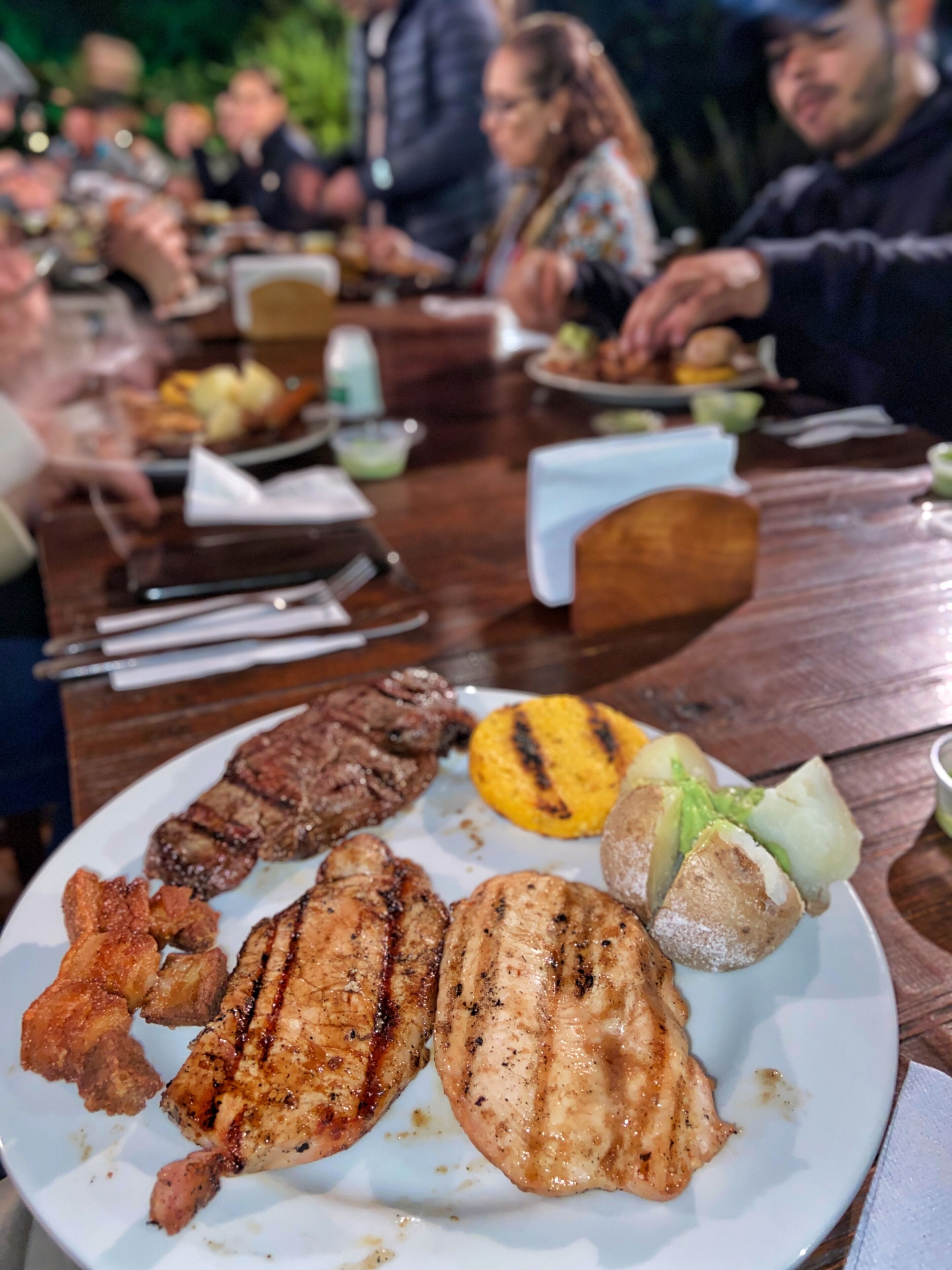 Une table à manger avec différentes sortes de viandes et de légumes grillés.