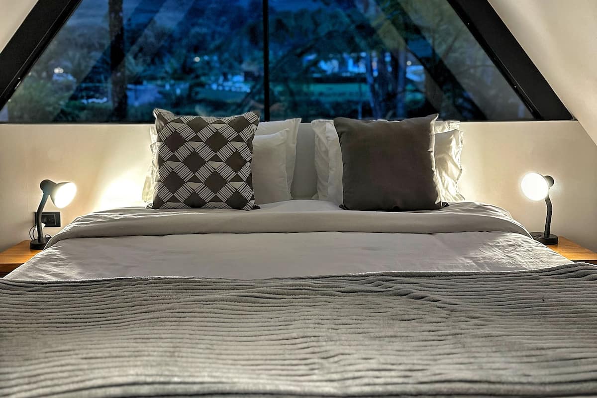 A bedroom with a bed, pillows, and bedside lamps.