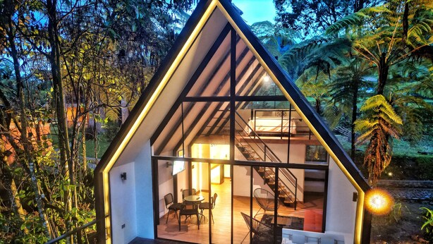 A modern, triangular-shaped cabin with a glass facade, a hot tub, and a staircase leading to a loft bedroom. - Avalon Hotel Campestre en Jardin (Jardin)
